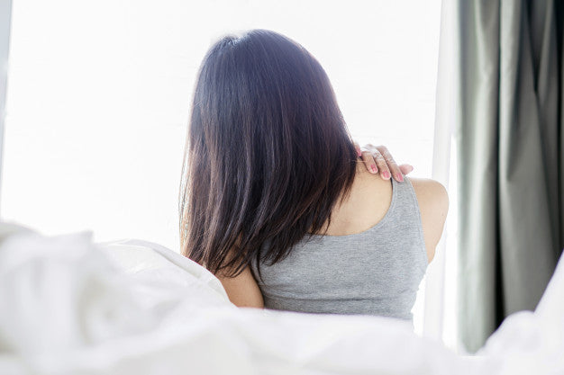 A woman waking up with back pain in bed