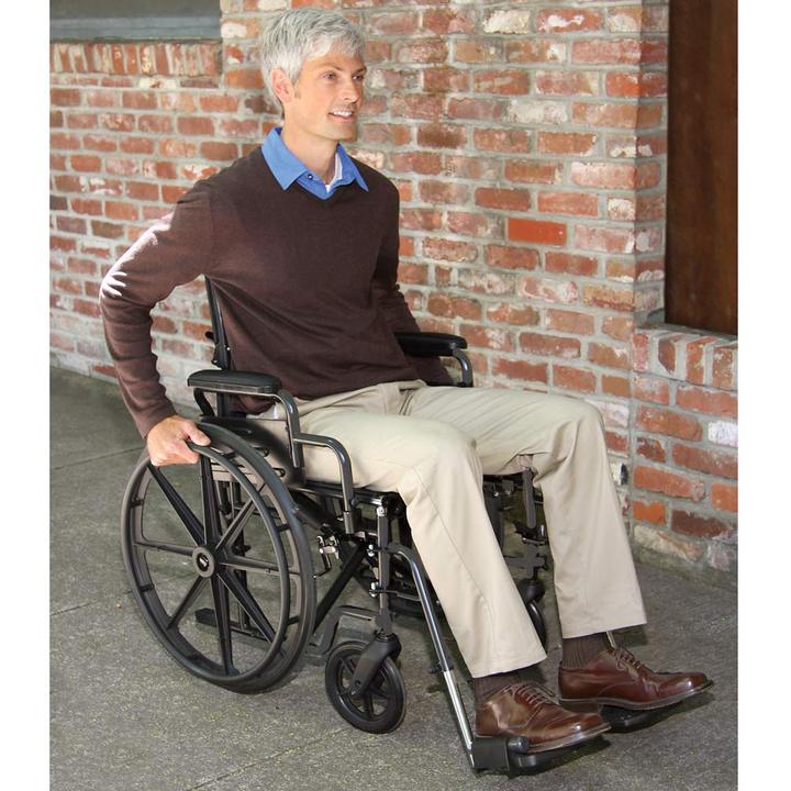 A man pushing himself while sitting in the Carex Wheelchair in front of a brick wall