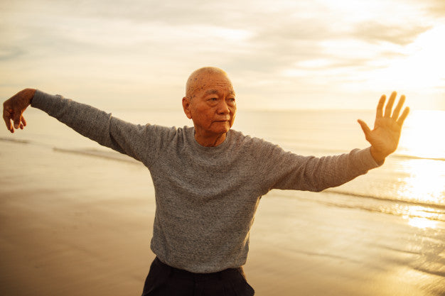 A senior man doing tai chi on a beach