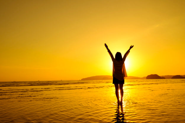 A person standing in water with her arms up