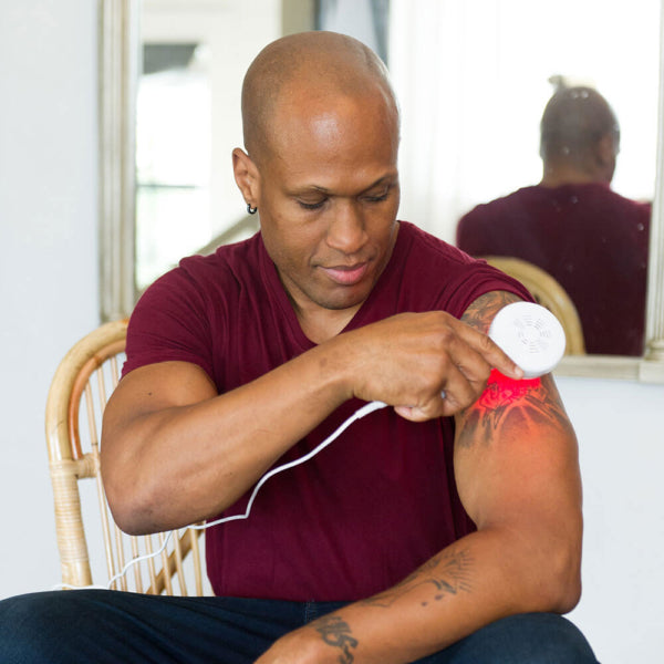  A man using the DPL Clinical Handheld Light Therapy on his arm 