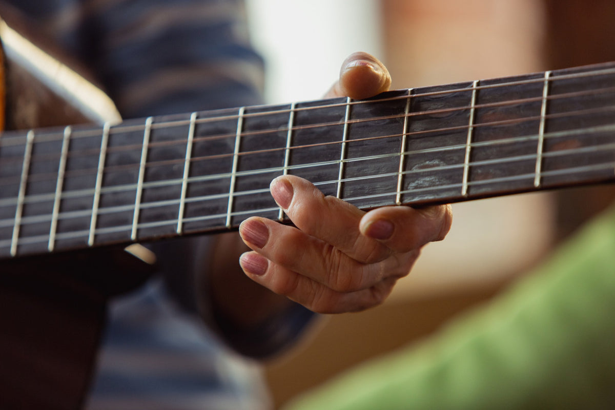 A close up of a person’s hand playing guitar