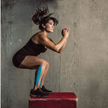 A woman jumping on a box with kinesiology tap on her leg