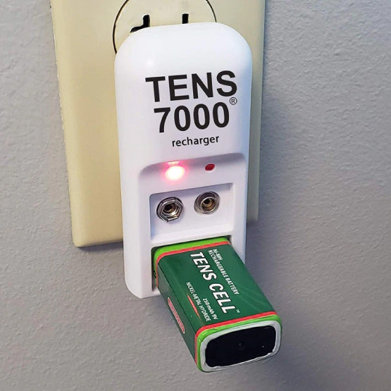 The TENS 7000 charger plugged into a wall outlet with a battery charging