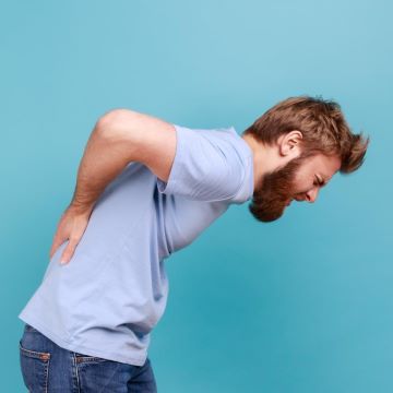 A man bending over holding his lower back in pain