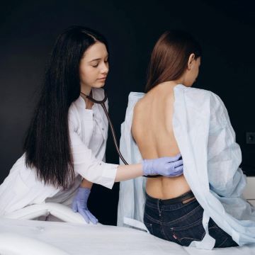 A doctor checking a woman’s lower back