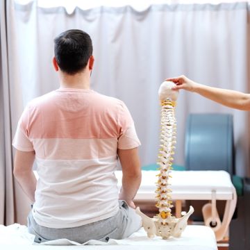 A man sitting on a table next to a fake spine