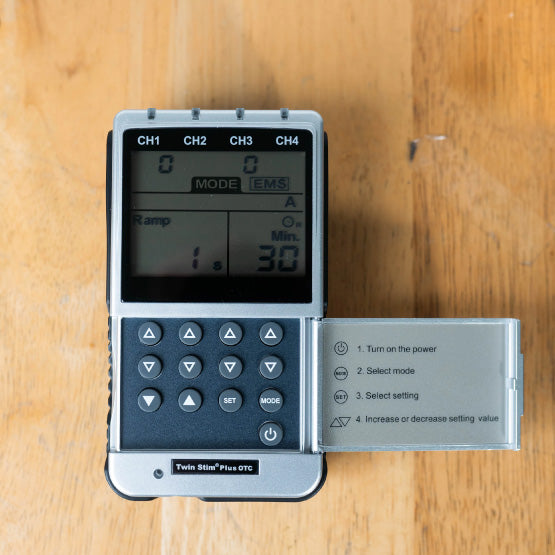 The Twin Stim Plus TENS Unit on a wood surface with its cover open