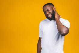 A man experiencing neck pain holding his neck