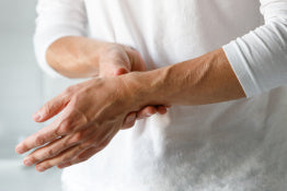 An elderly woman holding her wrist from arthritis