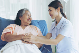 A nurse sitting next to a woman in a hospital bed