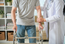 A caregiver helping a man use a walker