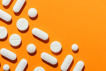 Various white pills on an orange background