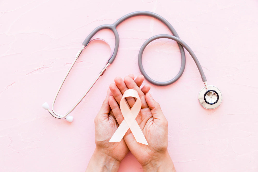 Hands holding a pink ribbon with a stethoscope