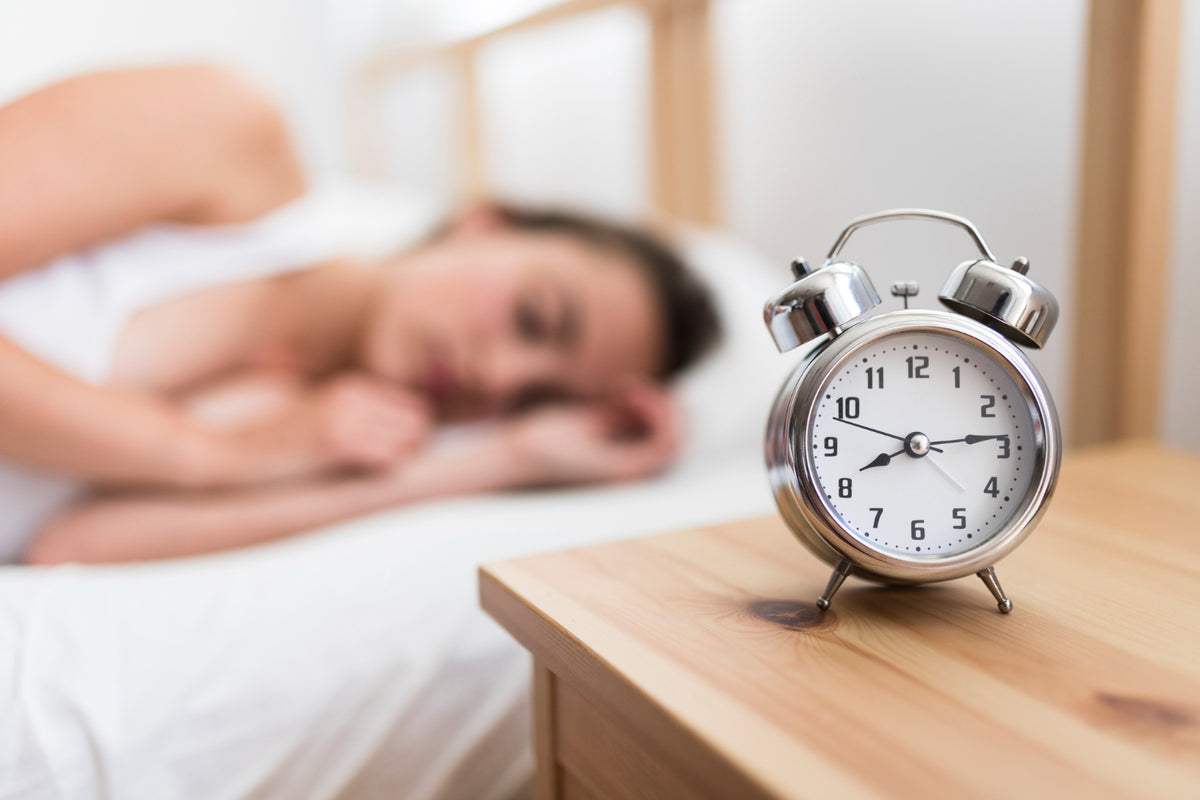 A clock next to a woman sleeping