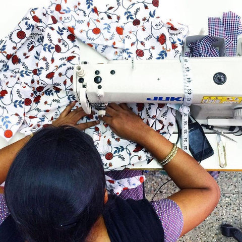 An Indian artisan sewing a Passion Lilie garment.