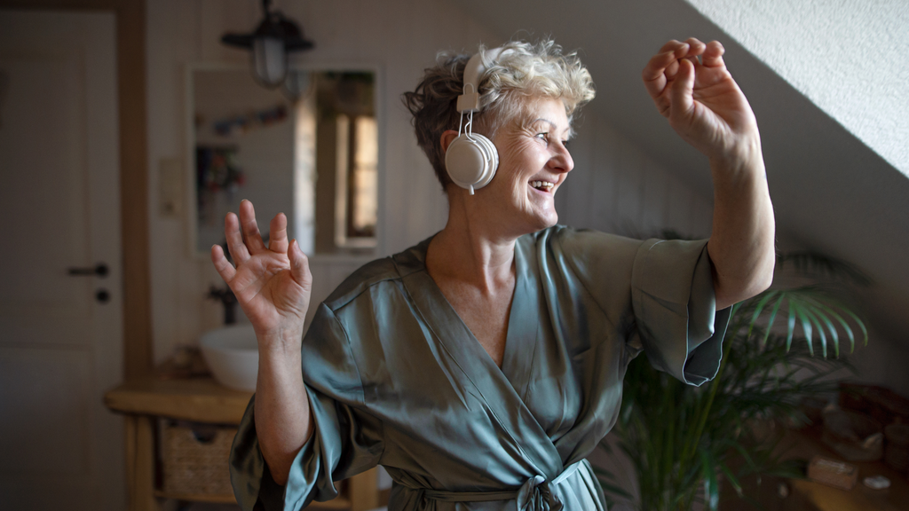 Woman dances wearing headphones in the living room