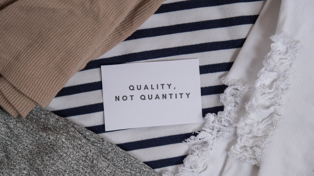 A sign that says "Quality not quantity" on an arrangement of fabric