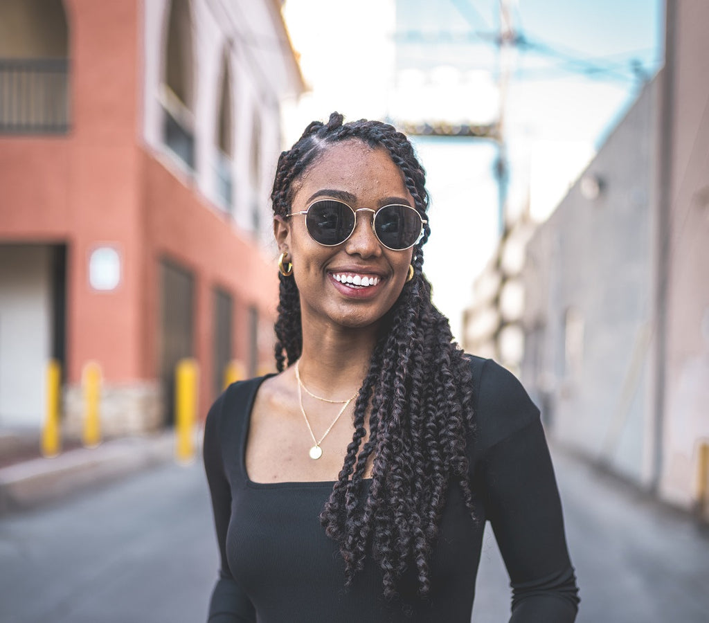 Black woman smiles wearing black top and sunglasses