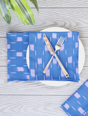 Blue, purple and white napkins on a white plate with silverware