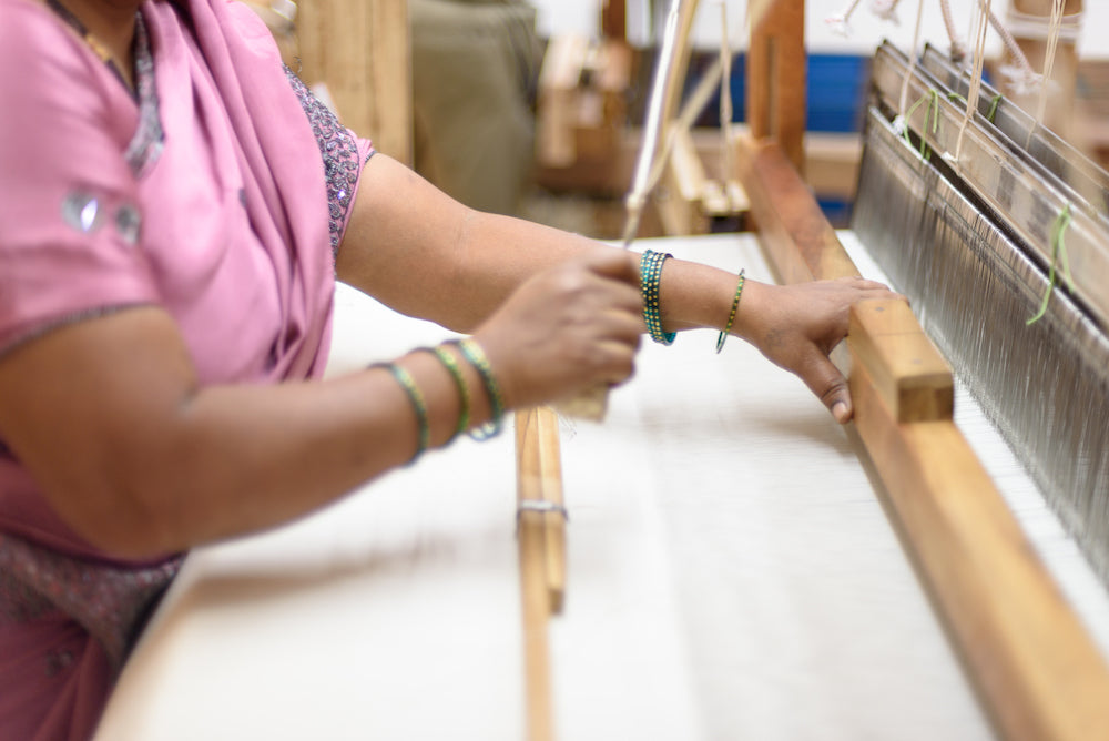Woman garment worker in India hand weaves fair trade fabric