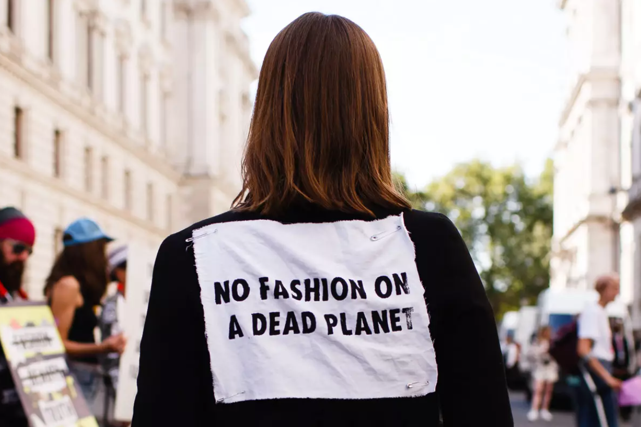Woman at a protest wears shirt that says "No fashion on a dead planet"