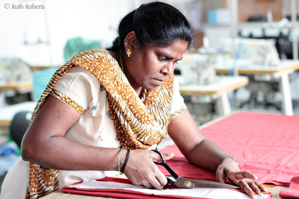 A fair trade artisan cuts fabric.