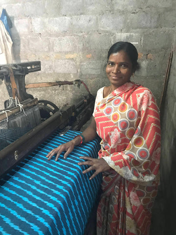 One of Passion Lilie's fair trade artisans from India, pictured here smiling while looming fabric.