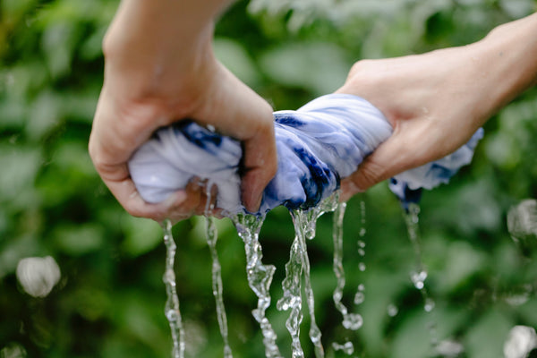 Hands wring water out of white and blue cloth