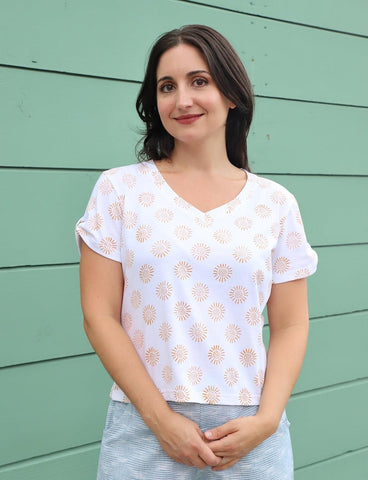Woman wears white t-shirt with sunshine print against a green wall