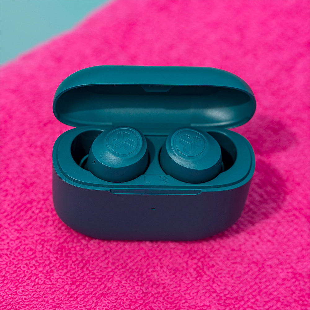 Go Air Pop True Wireless Earbuds in color Teal inside charging case against pink textured background