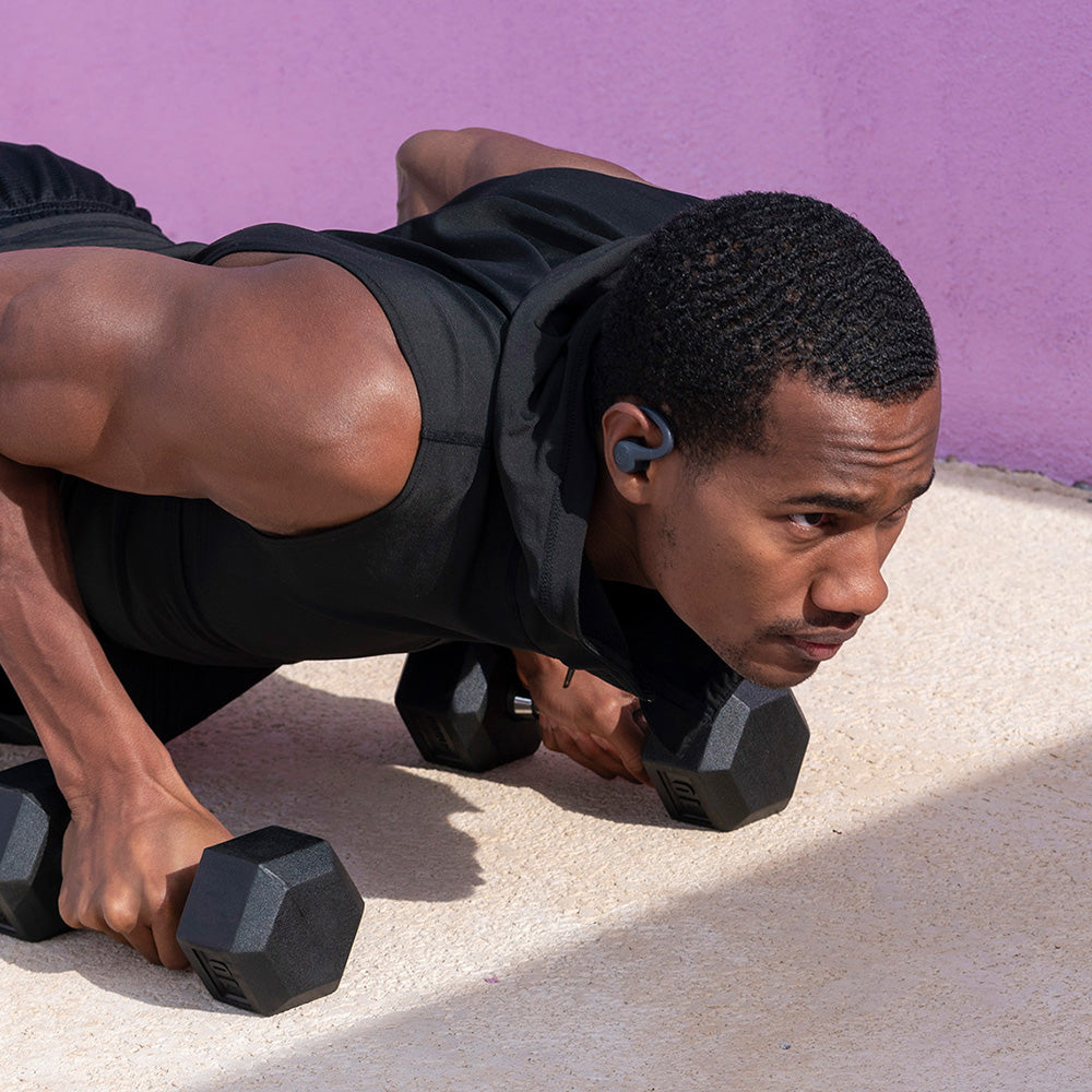 Man doing pushups with weights wearing GO Air Sport True Wireless Earbuds in Graphite