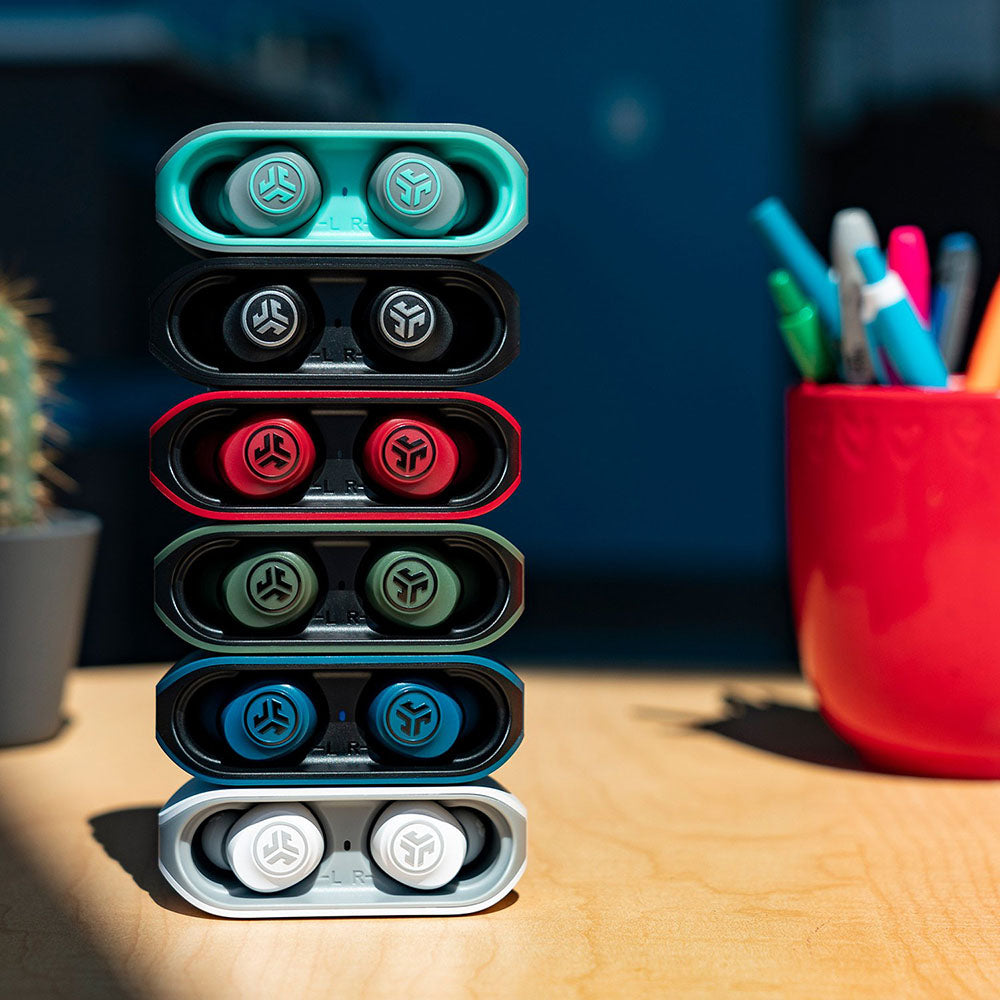 All colors of GO Air Earbuds stacked in their respective charging cases on a desk