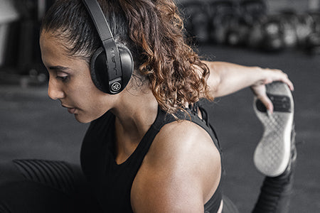 Woman Stretching in Gym Wearing Flex Sport Wireless Bluetooth Headphones