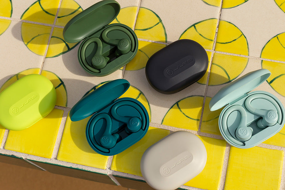 Photo of all colors Go Air Sport True Wireless Earbuds on patterned background in respective charging cases