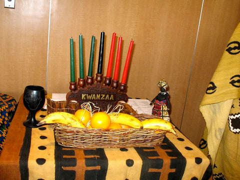 A table set with a kinara, fruit, and small statues.