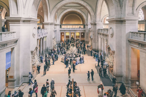Interior of the Metropolitan Museum of Art, main atrium. A busy hall with white stone arches.
