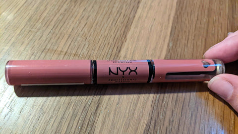 A duel-ended tube of liquid lipstick. One end is solid pink while the other contains clear liquid.
