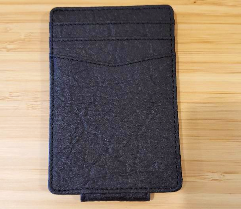 A black textured card holder wallet on a wooden table.