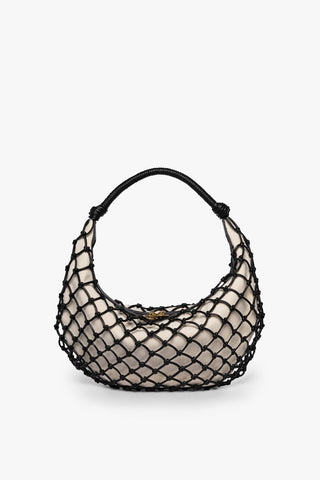 A small beige bag with black fishnetting around the outside of it and a circular top handle.