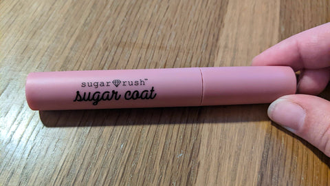 A tube of liquid lipstick. The tube is bright pink and labeled with the brand and product line in black cursive.