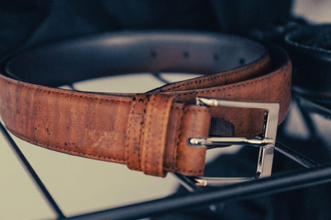 A brown leather belt on a black wire frame.