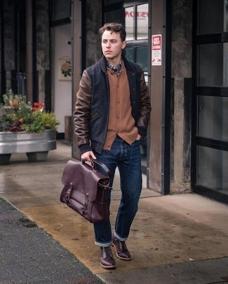 A man in a bomber jacket holds a burgandy briefcase by the top handles.