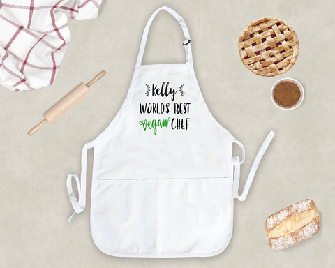 A white kitchen apron that reads "Kelly, World's Best Vegan Chef" in modern calligraphy font.