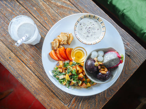 A breakfast plate featuring fruit, yogurt, and breakfast hash.