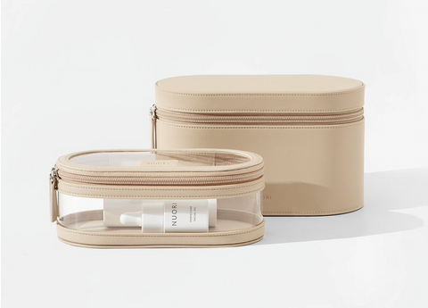 A set of two tan travel cases. In back, a plain zippered oval-shaped case. In front, a smaller zippered oval-shaped case with clear plastic sides and a clear plastic lid.