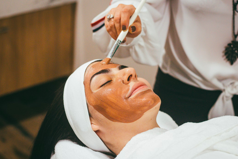 A woman has a brown face mask applied professionally.