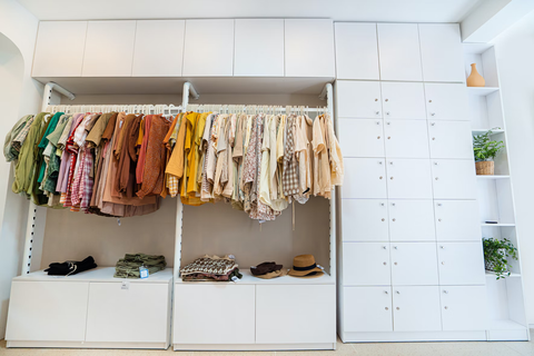A white walk in closet with the clothes organized by color.