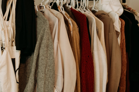 A row of brown and tan clothes on hangers.