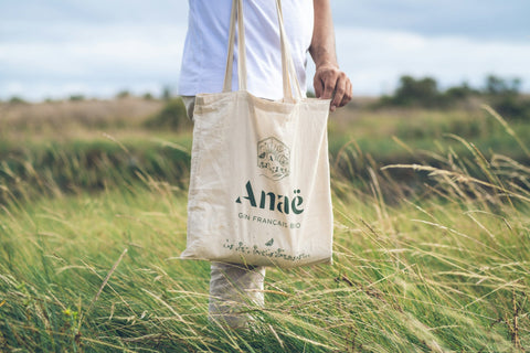 A white canvas tote bag with green graphics and writing.